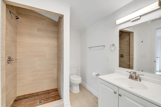 bathroom featuring vanity, toilet, and a tile shower