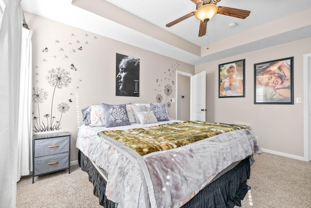 bedroom featuring ceiling fan, light colored carpet, and a tray ceiling