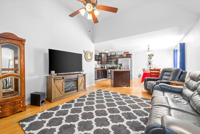 living room featuring light hardwood / wood-style flooring, ceiling fan, and a high ceiling