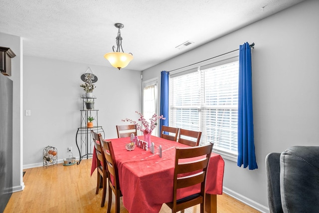 dining room with light hardwood / wood-style floors and a textured ceiling