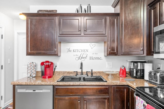 kitchen featuring stainless steel appliances, light stone countertops, dark brown cabinets, and sink