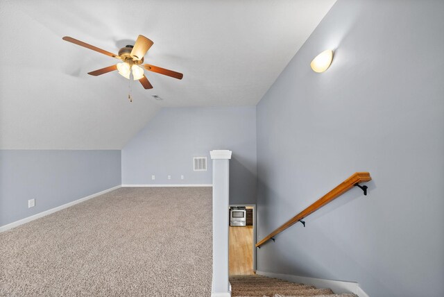 additional living space with ceiling fan, carpet floors, visible vents, baseboards, and vaulted ceiling