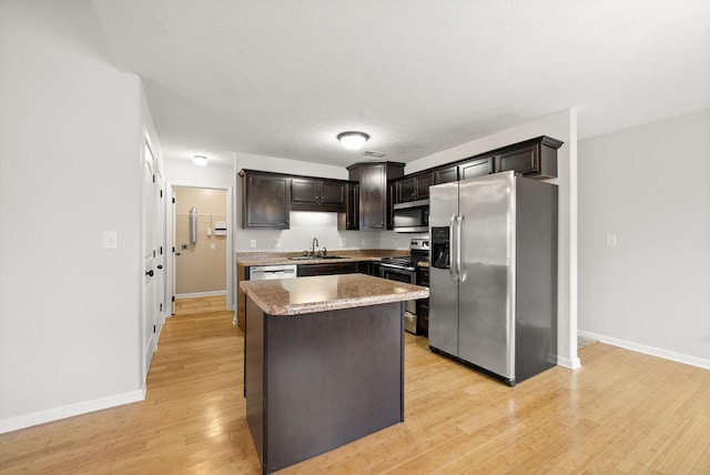 kitchen with light wood-type flooring, a kitchen island, baseboards, and stainless steel appliances