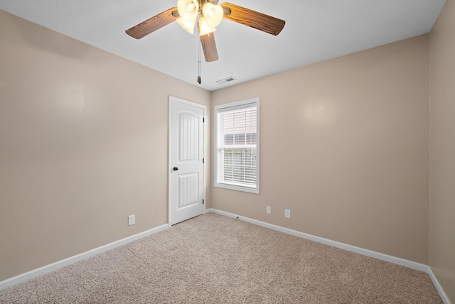 empty room with ceiling fan, carpet floors, visible vents, and baseboards