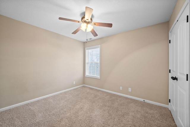 spare room with carpet, visible vents, baseboards, and ceiling fan