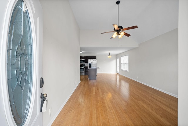 unfurnished living room featuring lofted ceiling, baseboards, ceiling fan, and light wood finished floors