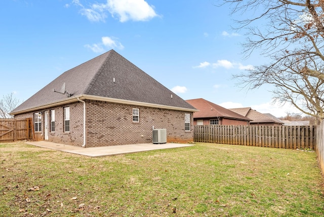 rear view of property featuring brick siding, a yard, a patio, central AC unit, and a fenced backyard