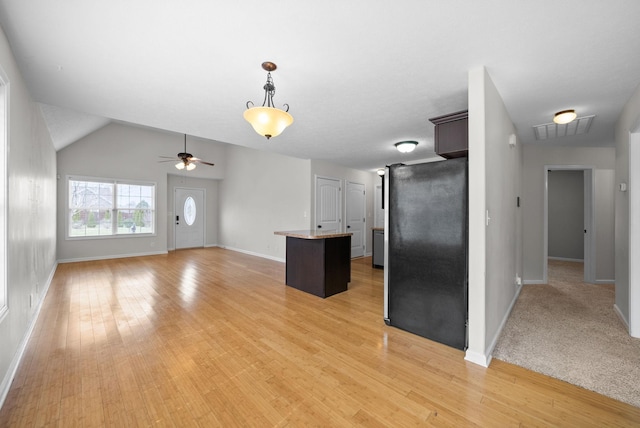 kitchen featuring pendant lighting, visible vents, light wood-style flooring, freestanding refrigerator, and a kitchen island