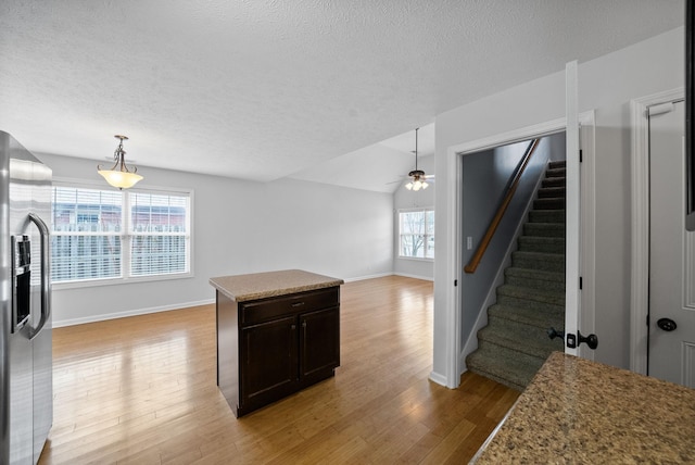 kitchen featuring hanging light fixtures, light wood finished floors, stainless steel fridge with ice dispenser, and a textured ceiling