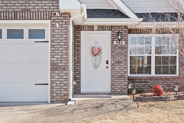 property entrance featuring an attached garage and brick siding