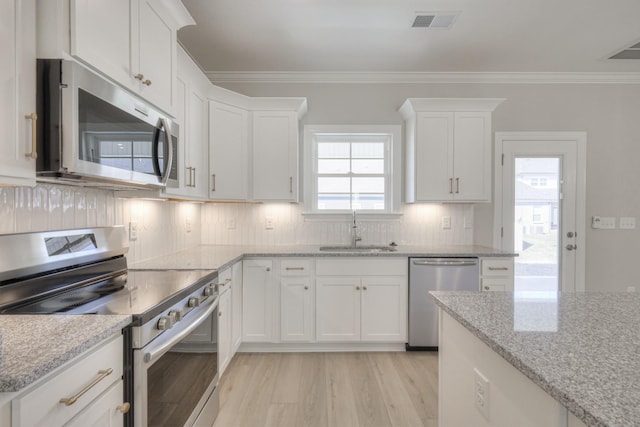 kitchen with light stone counters, sink, stainless steel appliances, and white cabinets