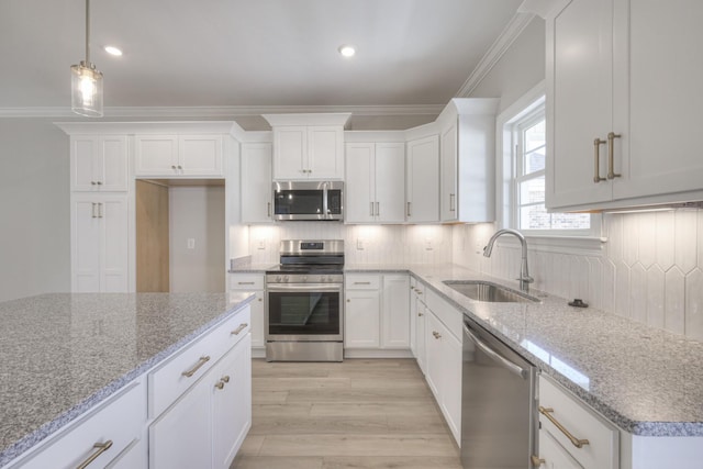 kitchen with sink, decorative light fixtures, ornamental molding, stainless steel appliances, and light stone countertops