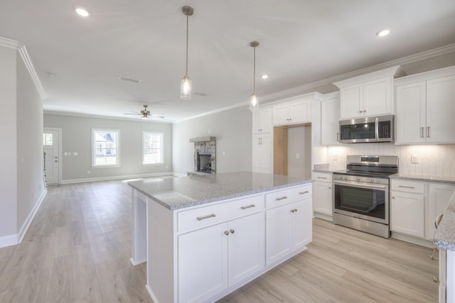 kitchen featuring stainless steel appliances, hanging light fixtures, a kitchen island, and white cabinets