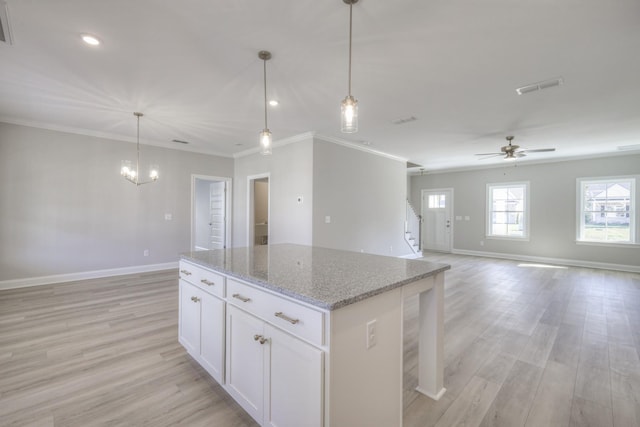 kitchen featuring white cabinetry, hanging light fixtures, light stone counters, and light wood-type flooring