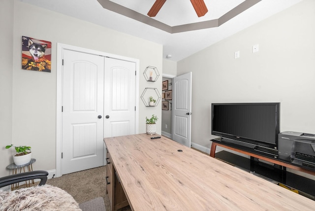 office space featuring a raised ceiling, ceiling fan, and carpet