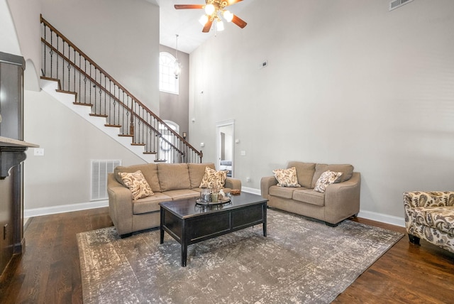 living room with a towering ceiling, dark hardwood / wood-style floors, and ceiling fan