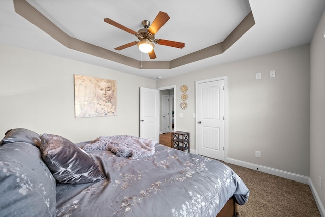 carpeted bedroom featuring a tray ceiling and ceiling fan