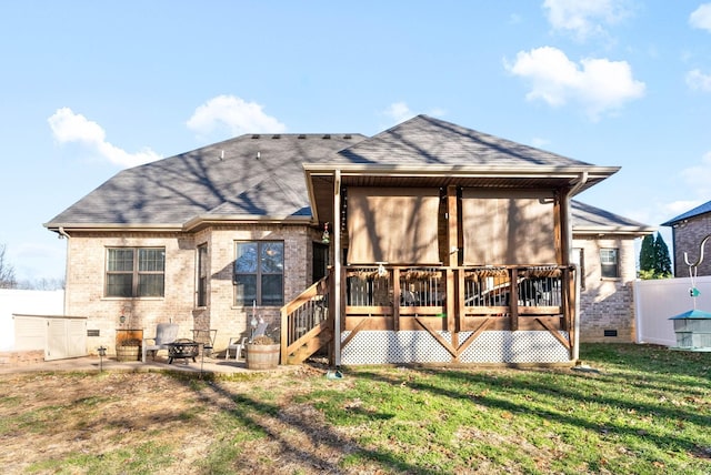 back of property with a wooden deck, a fire pit, and a lawn