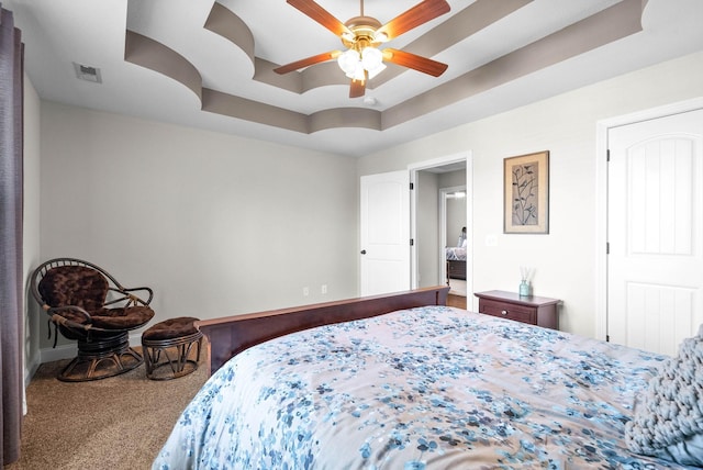 bedroom featuring a tray ceiling, carpet floors, and ceiling fan