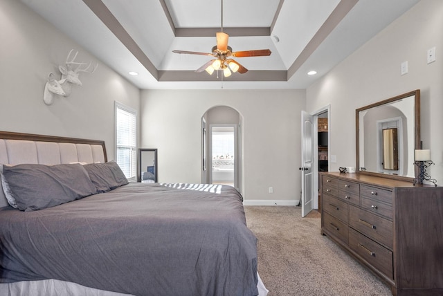 carpeted bedroom featuring a tray ceiling and ceiling fan