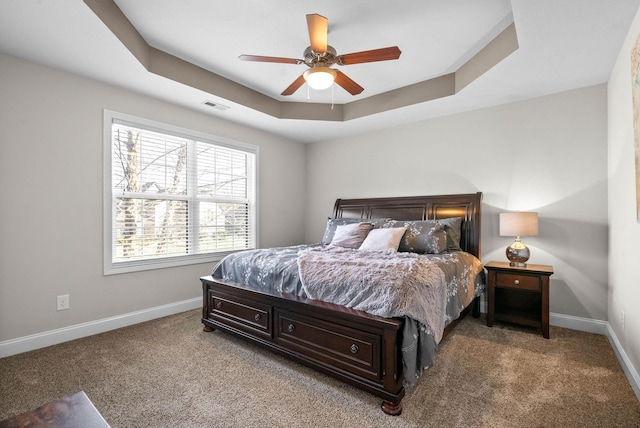 carpeted bedroom featuring ceiling fan and a raised ceiling