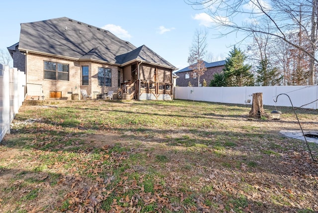 back of property with a sunroom and a lawn