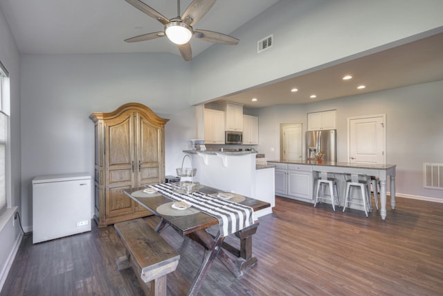 dining area with dark hardwood / wood-style flooring, a towering ceiling, and ceiling fan