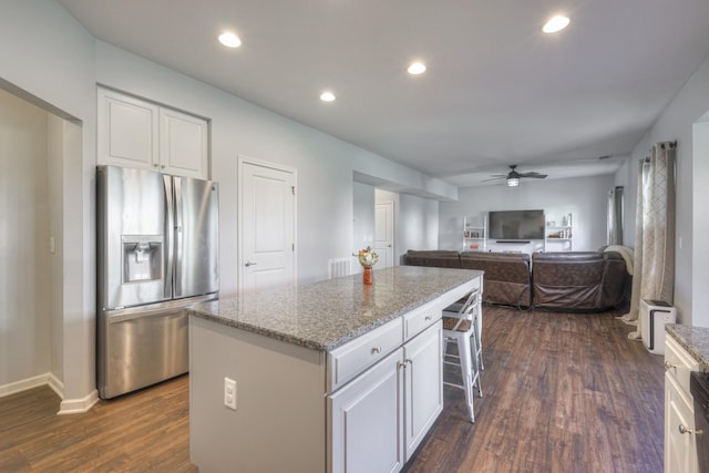 kitchen featuring a kitchen island, dark hardwood / wood-style floors, white cabinets, stainless steel fridge, and light stone counters