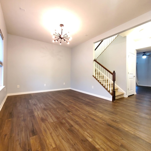 empty room with dark wood-type flooring and a chandelier