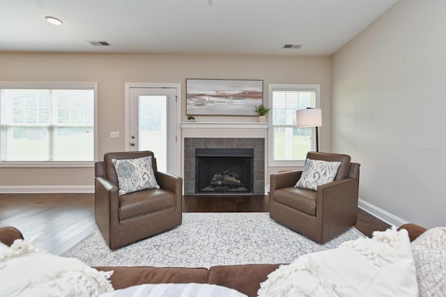 living room with a tile fireplace and hardwood / wood-style floors