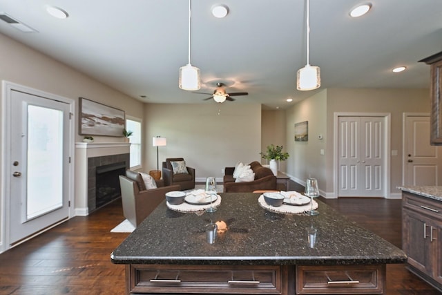 kitchen featuring pendant lighting, a center island, dark brown cabinets, and dark stone countertops