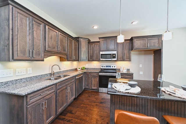 kitchen featuring dark stone countertops, sink, decorative light fixtures, and appliances with stainless steel finishes