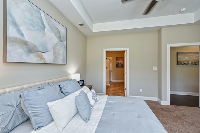 carpeted bedroom with ceiling fan, a spacious closet, a closet, and a raised ceiling