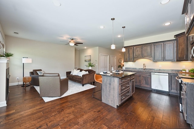 kitchen with a kitchen island, decorative light fixtures, dark stone counters, dark brown cabinetry, and stainless steel appliances