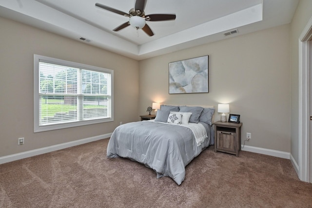 carpeted bedroom with a tray ceiling and ceiling fan