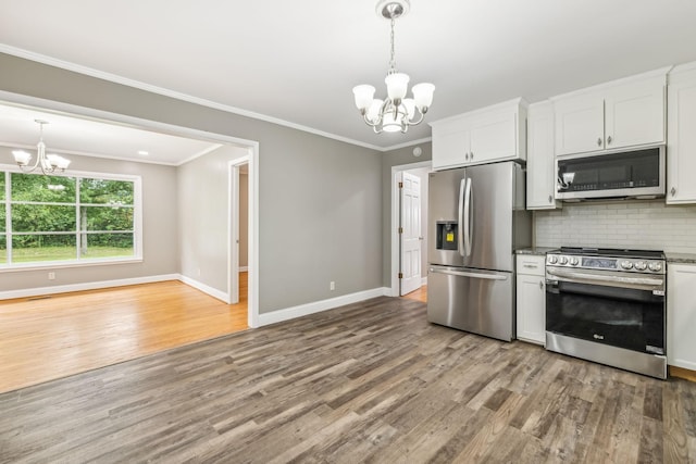 kitchen with pendant lighting, white cabinetry, stainless steel appliances, a notable chandelier, and decorative backsplash