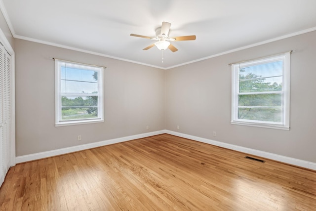 unfurnished bedroom featuring crown molding, a closet, light hardwood / wood-style floors, and multiple windows