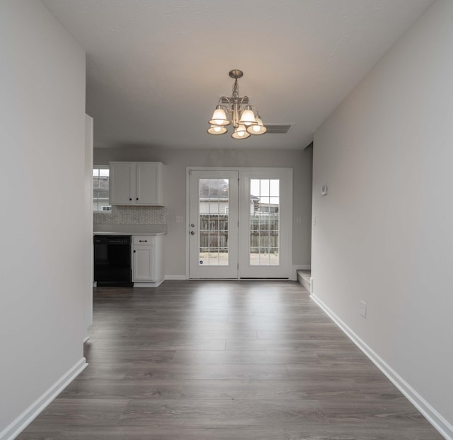 unfurnished dining area with hardwood / wood-style flooring and a notable chandelier