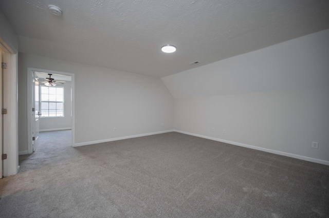 bonus room with carpet flooring, vaulted ceiling, and a textured ceiling