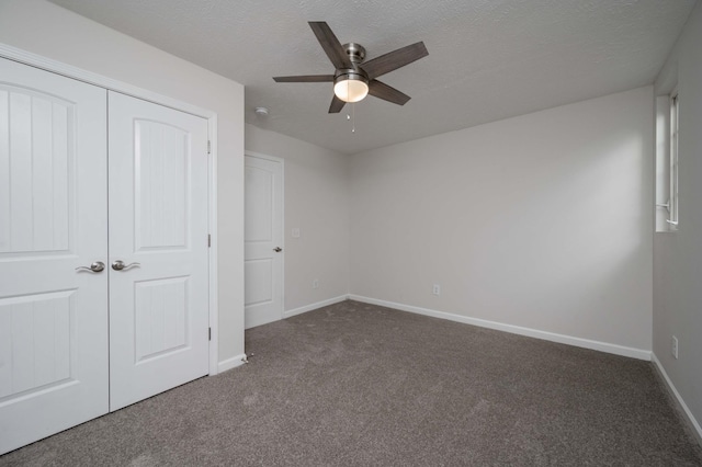 unfurnished bedroom featuring ceiling fan, dark carpet, a closet, and a textured ceiling