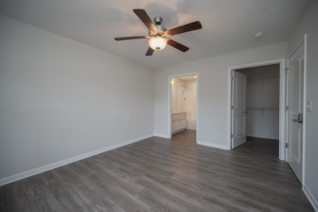 unfurnished bedroom with dark hardwood / wood-style flooring, a spacious closet, ceiling fan, ensuite bath, and a closet