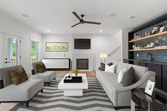 living room with hardwood / wood-style flooring, sink, and ceiling fan