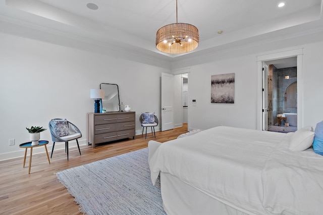 bedroom with a raised ceiling and light hardwood / wood-style flooring