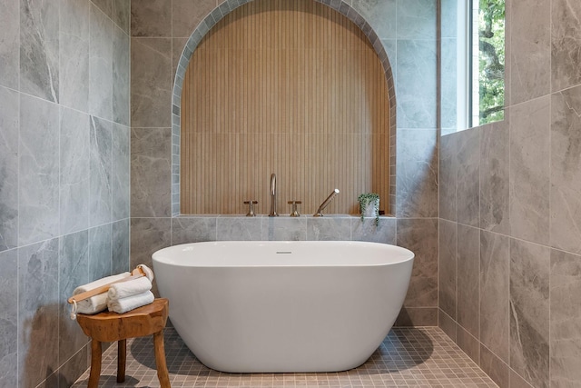 bathroom with tile walls and a tub