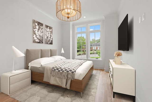 bedroom featuring a notable chandelier, ornamental molding, and light wood-type flooring