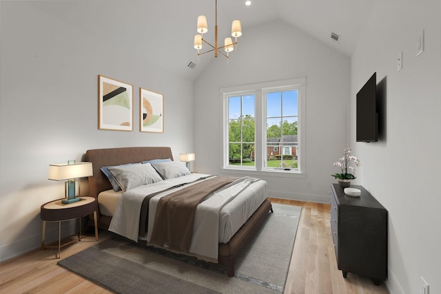 bedroom with high vaulted ceiling, a chandelier, and light wood-type flooring