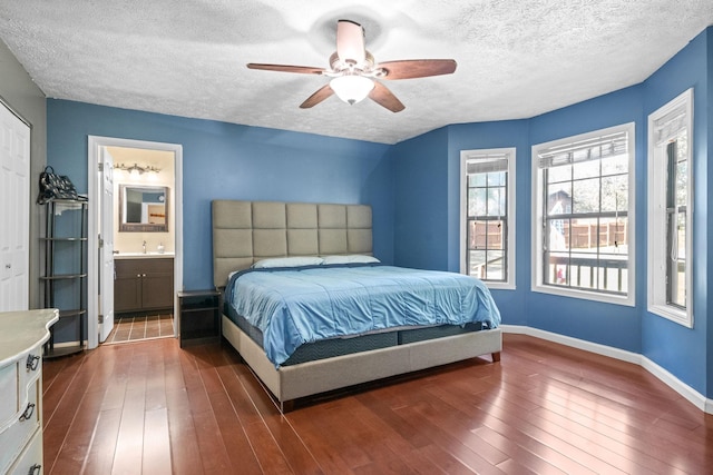 bedroom featuring sink, ensuite bath, a textured ceiling, dark hardwood / wood-style flooring, and ceiling fan