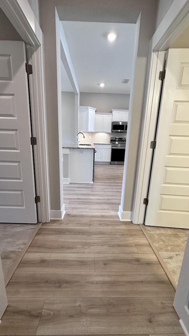 hallway featuring sink and light hardwood / wood-style floors