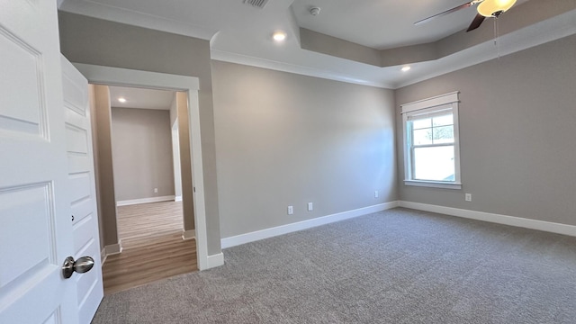 empty room with ceiling fan, ornamental molding, a tray ceiling, and carpet