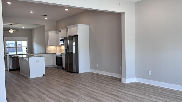 kitchen featuring ceiling fan, stainless steel appliances, a breakfast bar area, and white cabinets